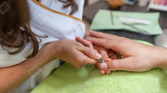 Manicurist using cuticle nippers on a male client