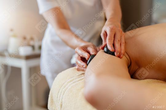 Massage therapist using hot stones on a client