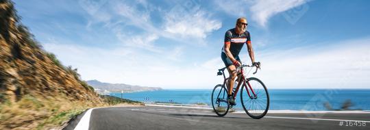 Mature Adult on a racing bike climbing the hill at mediterranean sea landscape coastal road  : Stock Photo or Stock Video Download rcfotostock photos, images and assets rcfotostock | RC-Photo-Stock.: