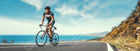 Mature Adult on a racing bike climbing the hill at mediterranean sea landscape coastal road  : Stock Photo or Stock Video Download rcfotostock photos, images and assets rcfotostock | RC Photo Stock.: