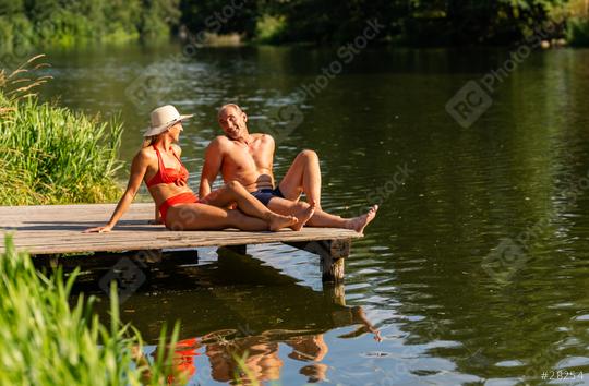 Mature couple relaxing on a dock by the lake, the woman in a hat and man smiling at each other  : Stock Photo or Stock Video Download rcfotostock photos, images and assets rcfotostock | RC Photo Stock.: