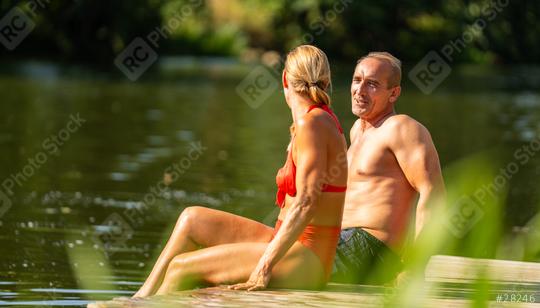 Mature couple sitting on a wooden dock by a lake, enjoying a serene moment together on a sunny day atr summer in germany  : Stock Photo or Stock Video Download rcfotostock photos, images and assets rcfotostock | RC Photo Stock.: