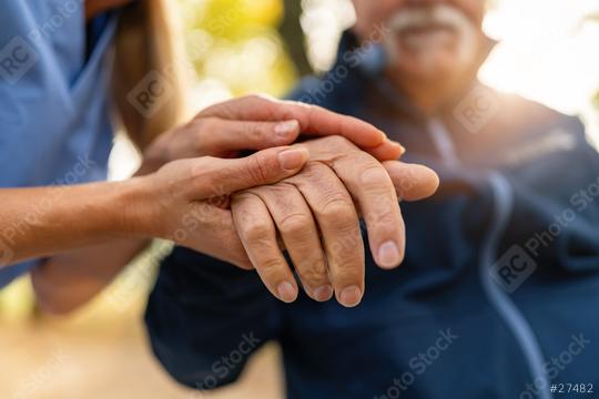 nurse comforting an elderly man in a wheelchair by holding his hands, both partly visible in a sunlit outdoor setting, offering comfort and support   : Stock Photo or Stock Video Download rcfotostock photos, images and assets rcfotostock | RC Photo Stock.: