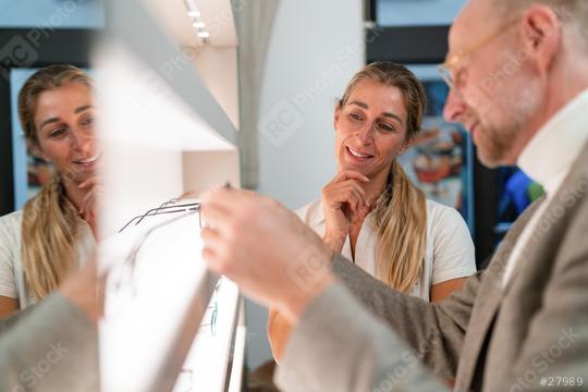 Optician and customer discussing eyeglasses. Looking at shelves with various eyeware in an optical shop.  : Stock Photo or Stock Video Download rcfotostock photos, images and assets rcfotostock | RC Photo Stock.: