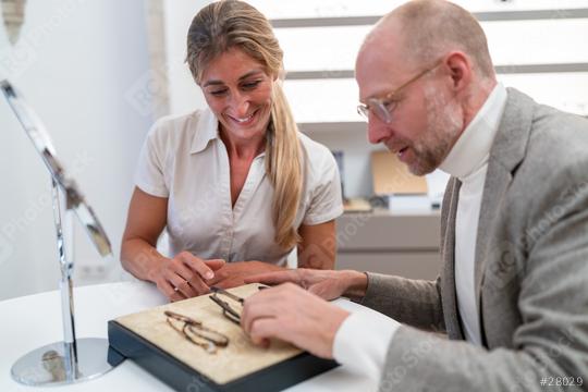 optician and customer examining eyeglasses on a display in an optical store  : Stock Photo or Stock Video Download rcfotostock photos, images and assets rcfotostock | RC Photo Stock.: