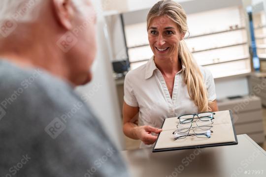 Optometrist presenting eyeglasses to elderly customer in optical store.  : Stock Photo or Stock Video Download rcfotostock photos, images and assets rcfotostock | RC Photo Stock.: