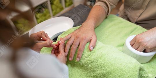 Over-the-shoulder shot of a manicure with a client soaking nail bed from his hand in a bowl and the other hand on the other hand a cuticle pusher being used on a fingernails in a beauty salon  : Stock Photo or Stock Video Download rcfotostock photos, images and assets rcfotostock | RC Photo Stock.: