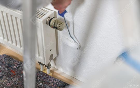 painter working with paint roller to paint behind a radiator the wall with white color. do it yourself concept image  : Stock Photo or Stock Video Download rcfotostock photos, images and assets rcfotostock | RC Photo Stock.: