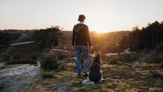Person and dog stands thoughtfully in nature and have a wonderful view of the landscape. At sunrise they look out into the distance The woman and the husky enjoy life, are happy and content.  : Stock Photo or Stock Video Download rcfotostock photos, images and assets rcfotostock | RC Photo Stock.: