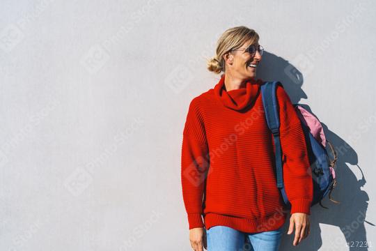 Portrait of a young woman with red sweater and backpack who looks to the right isolated on a concrete wall with copy space. Beautiful student girl looking sideways University concept image.  : Stock Photo or Stock Video Download rcfotostock photos, images and assets rcfotostock | RC Photo Stock.: