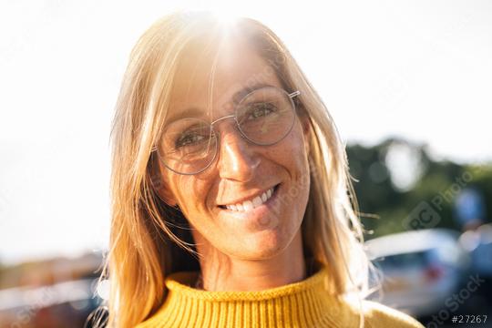 Portrait of beautiful woman smiling and looking at camera  with glasses during sunset. Outdoor portrait of a smiling girl. Happy cheerful girl laughing at city with yellow sweater.  : Stock Photo or Stock Video Download rcfotostock photos, images and assets rcfotostock | RC Photo Stock.: