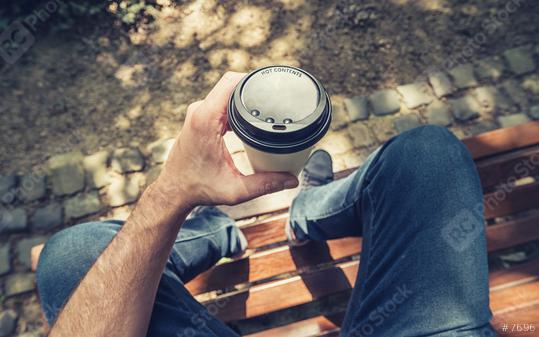 POV image of man sits on a bench and holding paper cup of coffee at a summer day in the park  : Stock Photo or Stock Video Download rcfotostock photos, images and assets rcfotostock | RC Photo Stock.: