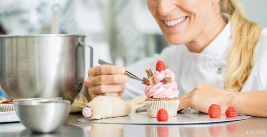 Professional women in pastry bakery as confectioner draped pieces of chocolate on a muffin topping with tweezers  : Stock Photo or Stock Video Download rcfotostock photos, images and assets rcfotostock | RC Photo Stock.: