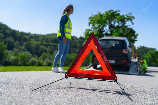 Red warning triangle on road with woman and tow truck in background. Roadside assistance concept image.   : Stock Photo or Stock Video Download rcfotostock photos, images and assets rcfotostock | RC Photo Stock.: