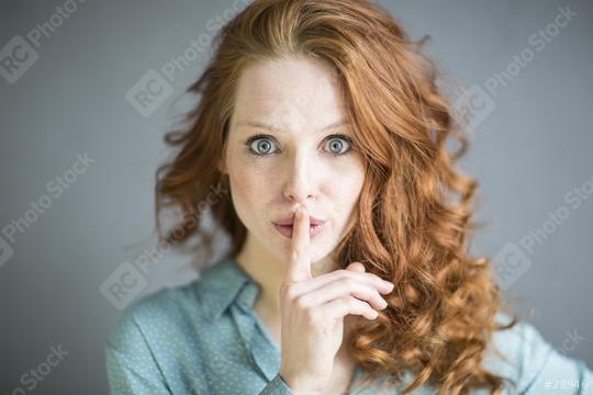 Red-haired woman with striking blue eyes making a quiet gesture by placing her finger on her lips, wearing a green blouse with a subtle pattern, against a soft gray background, expressing secrecy  : Stock Photo or Stock Video Download rcfotostock photos, images and assets rcfotostock | RC Photo Stock.: