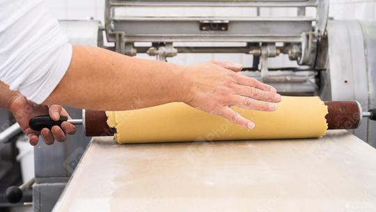 Rolling out cookie dough with a wooden rolling pin in a bakery, preparing the dough for cutting, with a hand steadying the dough in a professional baking environment  : Stock Photo or Stock Video Download rcfotostock photos, images and assets rcfotostock | RC Photo Stock.: