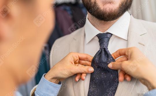 Saleswoman adjusting a tie on a man in a beige suit  : Stock Photo or Stock Video Download rcfotostock photos, images and assets rcfotostock | RC Photo Stock.: