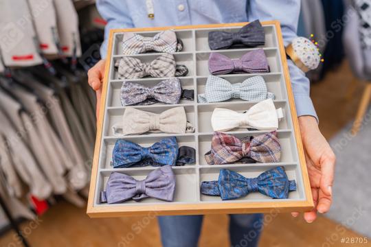 saleswoman holding a tray of various bow ties with a rack of suits in the background on a store  : Stock Photo or Stock Video Download rcfotostock photos, images and assets rcfotostock | RC Photo Stock.: