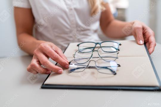 saleswomans hands adjusting eyeglasses on a display tray. focus on hands and glasses with blurred background. Optician Shop concept image.  : Stock Photo or Stock Video Download rcfotostock photos, images and assets rcfotostock | RC Photo Stock.: