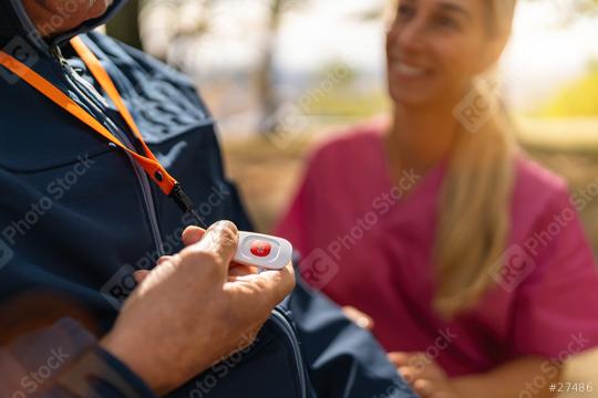 senior man holding an SOS alarm button on a lanyard while a caregiver smiles at him, blurred autumn background  : Stock Photo or Stock Video Download rcfotostock photos, images and assets rcfotostock | RC Photo Stock.: