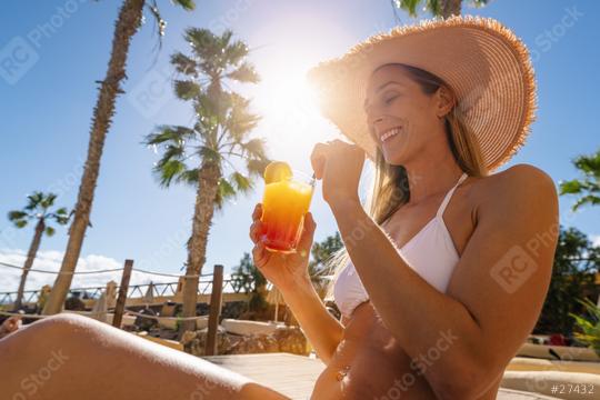 sexy woman in a white bikini and straw hat enjoys a tropical cocktail under the sun with palm trees in the background at a resort in caribbean island hotel  : Stock Photo or Stock Video Download rcfotostock photos, images and assets rcfotostock | RC Photo Stock.: