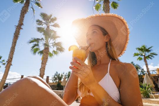 sexy woman in a white bikini and straw hat sipping a tropical drink under the palm trees at caribbean island hotel   : Stock Photo or Stock Video Download rcfotostock photos, images and assets rcfotostock | RC Photo Stock.: