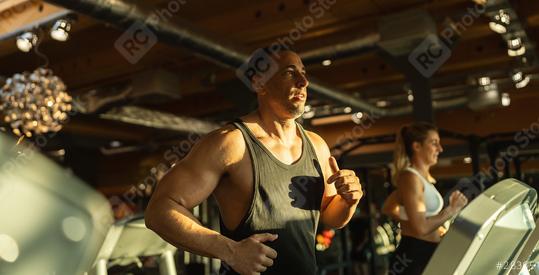 Side view of fit young man and woman while running side by side on modern electric treadmills at the gym  : Stock Photo or Stock Video Download rcfotostock photos, images and assets rcfotostock | RC Photo Stock.: