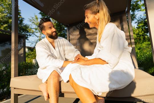 Smiling couple in love in white bathrobes sitting on an outdoor bench lounger  in sunlight at spa wellness hotel  : Stock Photo or Stock Video Download rcfotostock photos, images and assets rcfotostock | RC Photo Stock.: