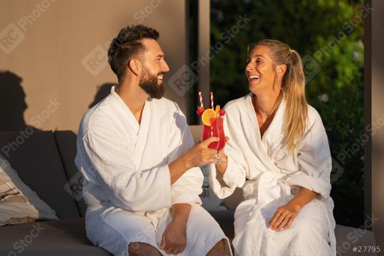 Smiling couple in white spa robes clinking cocktails in sunny ambiance at spa resort  : Stock Photo or Stock Video Download rcfotostock photos, images and assets rcfotostock | RC Photo Stock.: