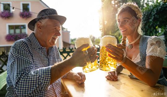 Smiling elderly man and young woman toasting beer mugs, traditional Bavarian outfits in beer garden or oktoberfest at Bavaria, Germany  : Stock Photo or Stock Video Download rcfotostock photos, images and assets rcfotostock | RC Photo Stock.: