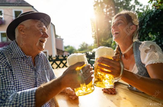 Smiling man and young woman toasting beer mugs, traditional Bavarian outfits in beer garden or oktoberfest at Bavaria, Germany  : Stock Photo or Stock Video Download rcfotostock photos, images and assets rcfotostock | RC Photo Stock.: