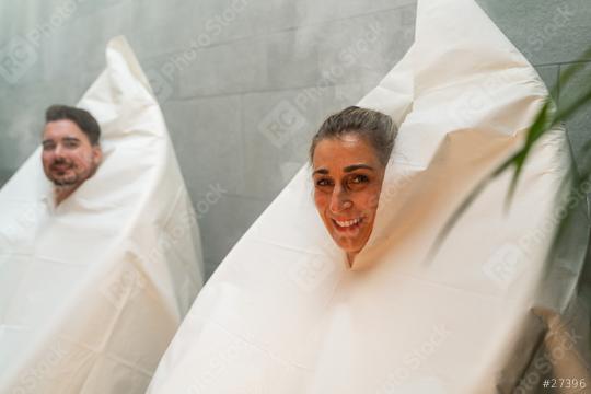 Smiling woman and man wrapped in thermal hot steam sauna bags in a spa hotel, steam and plants around  : Stock Photo or Stock Video Download rcfotostock photos, images and assets rcfotostock | RC Photo Stock.: