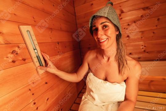 Smiling woman in a finish sauna wearing a felt hat and adjusting a wall-mounted hourglass at spa hotel  : Stock Photo or Stock Video Download rcfotostock photos, images and assets rcfotostock | RC Photo Stock.: