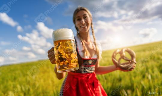 Smiling woman in Bavarian tracht offering beer and pretzel in a sunny  wheat field celebrating Oktoberfest festival in munich.  : Stock Photo or Stock Video Download rcfotostock photos, images and assets rcfotostock | RC Photo Stock.: