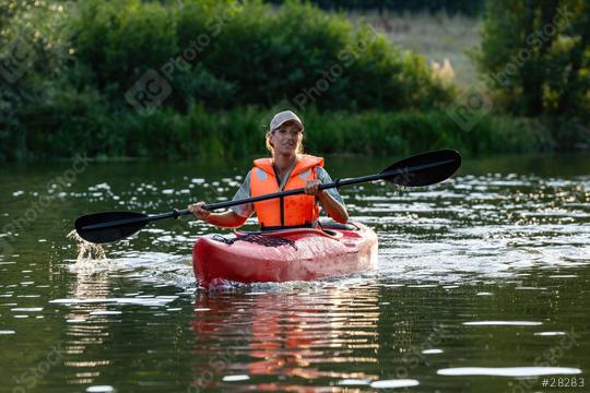 smiling woman kayaking on a calm river, paddling with a black oar, wearing an orange life jacket and cap in germany at summer. Kayak Water Sports concept image  : Stock Photo or Stock Video Download rcfotostock photos, images and assets rcfotostock | RC Photo Stock.: