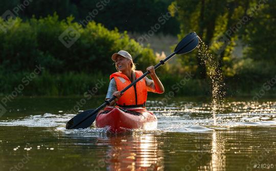 Smiling woman paddling a kayak on a serene river during golden hour. Kayak Water Sports concept image  : Stock Photo or Stock Video Download rcfotostock photos, images and assets rcfotostock | RC Photo Stock.: