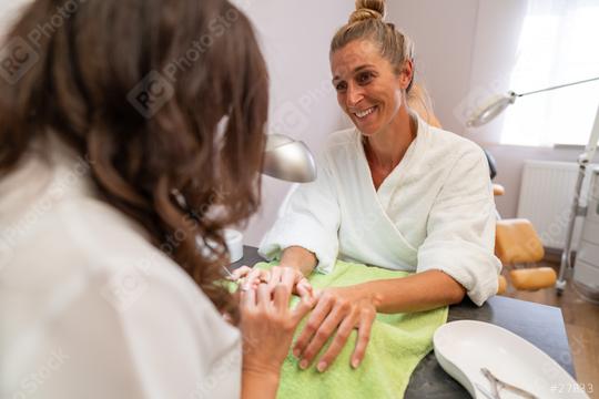 Smiling woman receiving a manicure in a beauty salon with a manicurist working on her nails  : Stock Photo or Stock Video Download rcfotostock photos, images and assets rcfotostock | RC Photo Stock.: