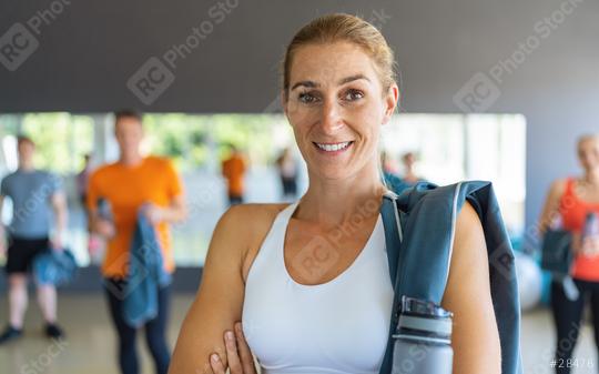 Smiling woman with gym bag and water bottle in a fitness center with people in background. Teamwork Concept image  : Stock Photo or Stock Video Download rcfotostock photos, images and assets rcfotostock | RC Photo Stock.: