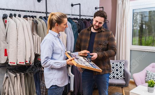 Tailor assisting a customer with choosing a bow tie, in a store with suits in background  : Stock Photo or Stock Video Download rcfotostock photos, images and assets rcfotostock | RC Photo Stock.: