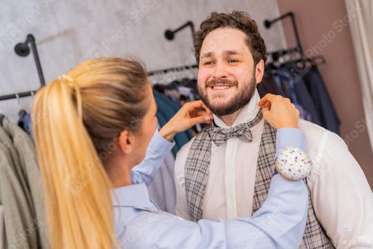 Tailor fitting a bow tie on a cheerful man in a fashion store with clothing racks
  : Stock Photo or Stock Video Download rcfotostock photos, images and assets rcfotostock | RC Photo Stock.: