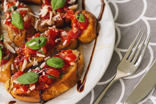 Tasty savory tomato Italian appetizers, or bruschetta, on slices of toasted baguette garnished with basil, on a Plate  : Stock Photo or Stock Video Download rcfotostock photos, images and assets rcfotostock | RC Photo Stock.: