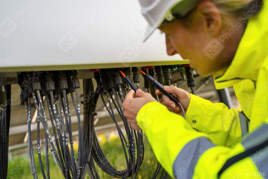 Technician using a voltage tester on a solar field