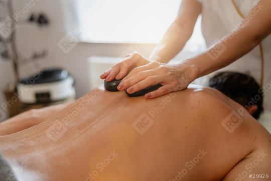 Therapist giving a hot stone massage to a client lying face down  : Stock Photo or Stock Video Download rcfotostock photos, images and assets rcfotostock | RC Photo Stock.: