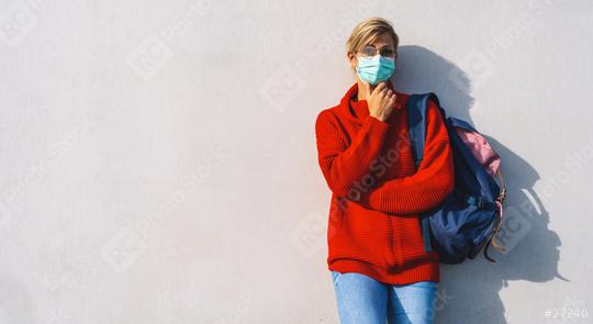 thoughtful woman in glasses and a teal face mask leans against a concrete wall. She wears a red sweater,jeans, and carries a backpack, with one hand resting beneath her chin, with copyspace  : Stock Photo or Stock Video Download rcfotostock photos, images and assets rcfotostock | RC Photo Stock.: