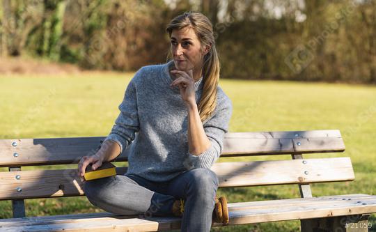 thoughtful woman sitting in the park on at a bench. student thinking with a book in the park concept image  : Stock Photo or Stock Video Download rcfotostock photos, images and assets rcfotostock | RC Photo Stock.: