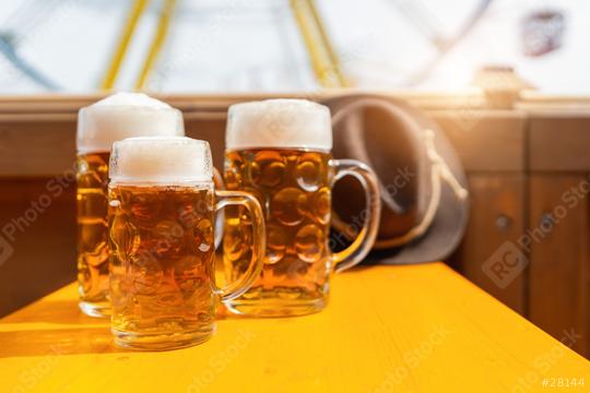 Three frothy beer mugs on a sunny  table in a beer tent with amusement rides in the background at oktoberfest or  dult in germany  : Stock Photo or Stock Video Download rcfotostock photos, images and assets rcfotostock | RC Photo Stock.: