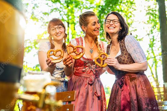 Three girl friends, having fun in beer garden holding traditional Bavaria pretzels in front of a wooden beer barrel at Oktoberfest, Munich, Germany  : Stock Photo or Stock Video Download rcfotostock photos, images and assets rcfotostock | RC Photo Stock.: