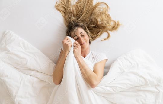 Top view of a satisfied young woman lying on a bed and cuddles with blanket at the bedroom  : Stock Photo or Stock Video Download rcfotostock photos, images and assets rcfotostock | RC Photo Stock.: