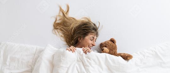 Top view of a woman that is surprise and looking to a teddy bear sleeping on white bed lying under blanket  : Stock Photo or Stock Video Download rcfotostock photos, images and assets rcfotostock | RC Photo Stock.: