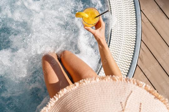 Top-down view of woman in whirlpool with drink, legs submerged, next to wooden deck  : Stock Photo or Stock Video Download rcfotostock photos, images and assets rcfotostock | RC Photo Stock.: